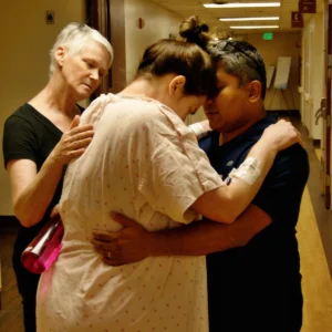 Couple slow dancing in the hospital hallway while doula offers comfort and support