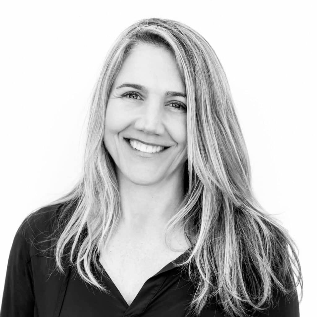 Black and white photo of a doula, a woman with blond hair looking into the camera