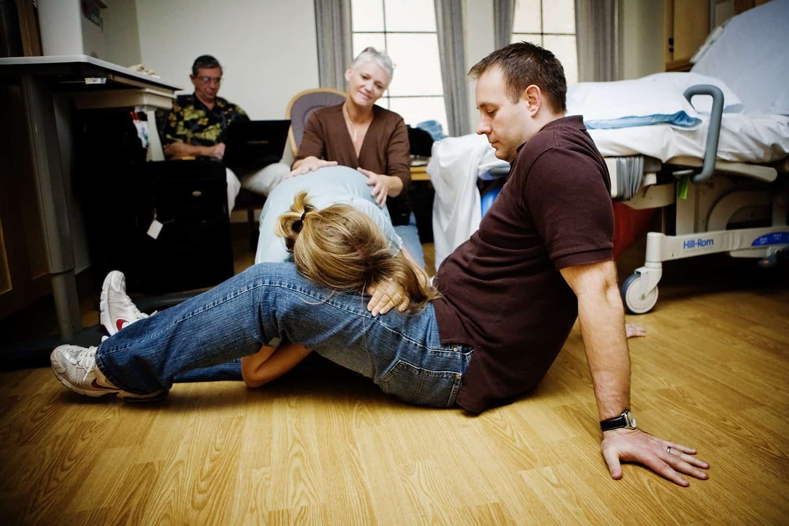 Husband supporting his wife during a contraction while the doula provides massage.