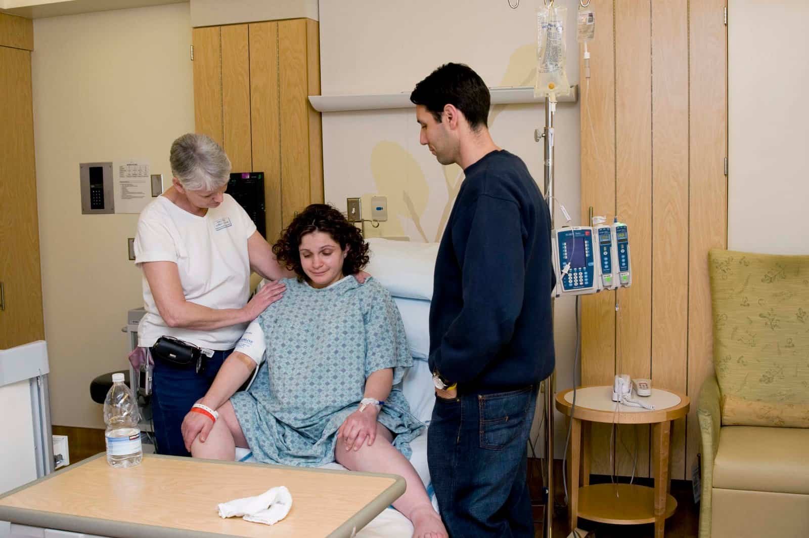 Doula comforting a labor woman while her partner stands by offering support.
