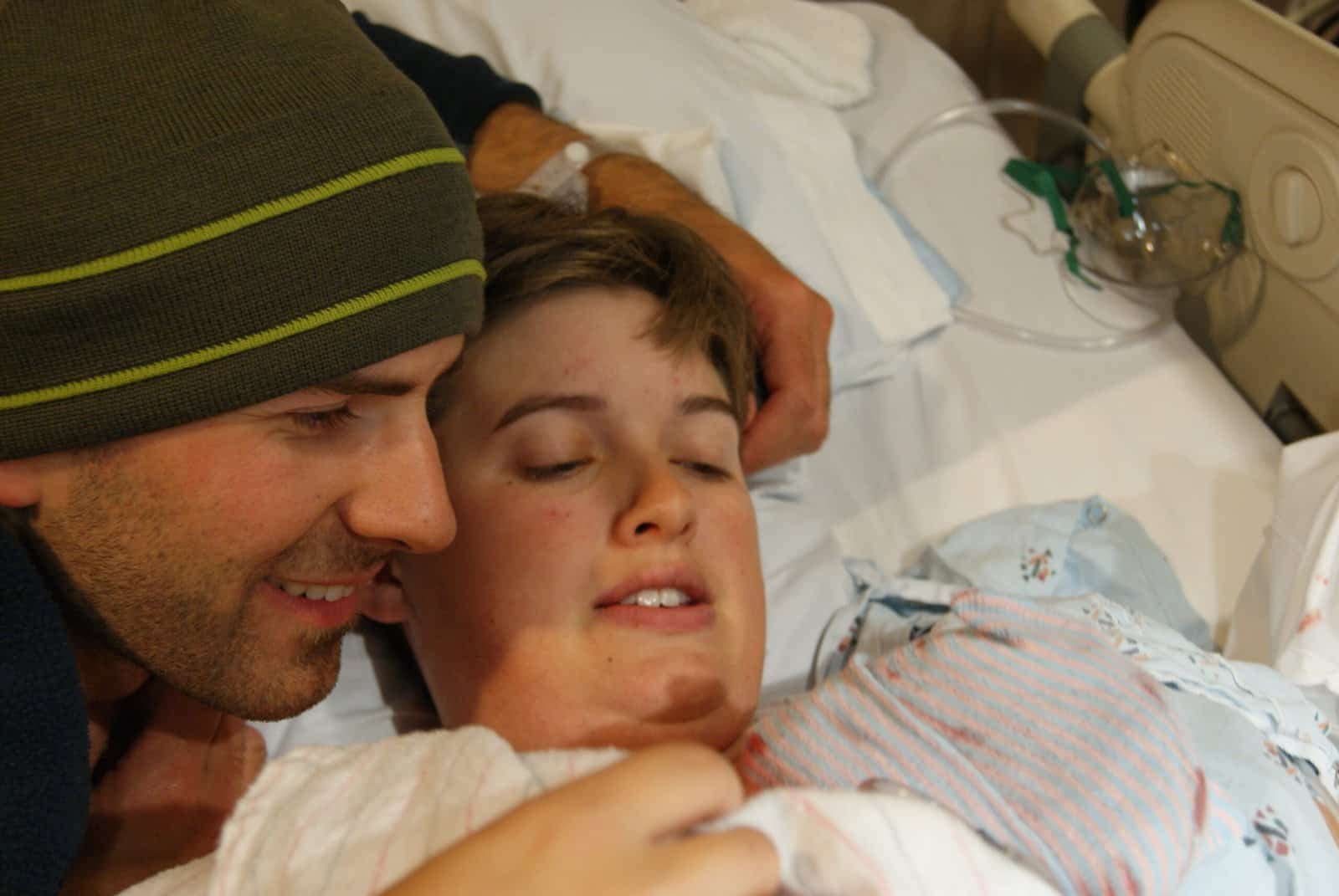 Happy new parents admiring their new baby after a vaginal birth at the hospital.