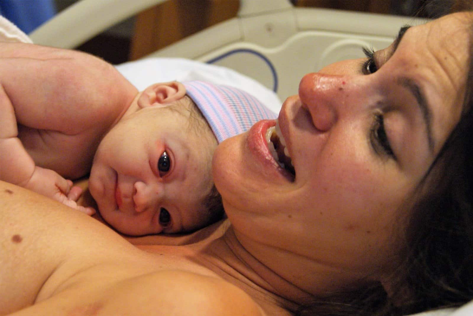 Beautiful new mother and baby, skin to skin in the hospital delivery room.