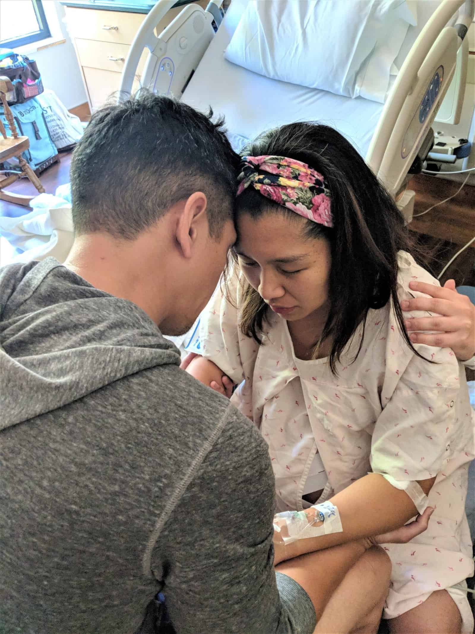Woman receiving virtual birth support from partner in hospital room.